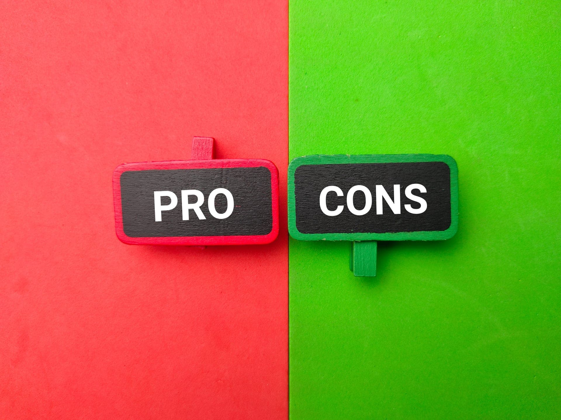 Two black signs with the words pro and cons on a red and green surface