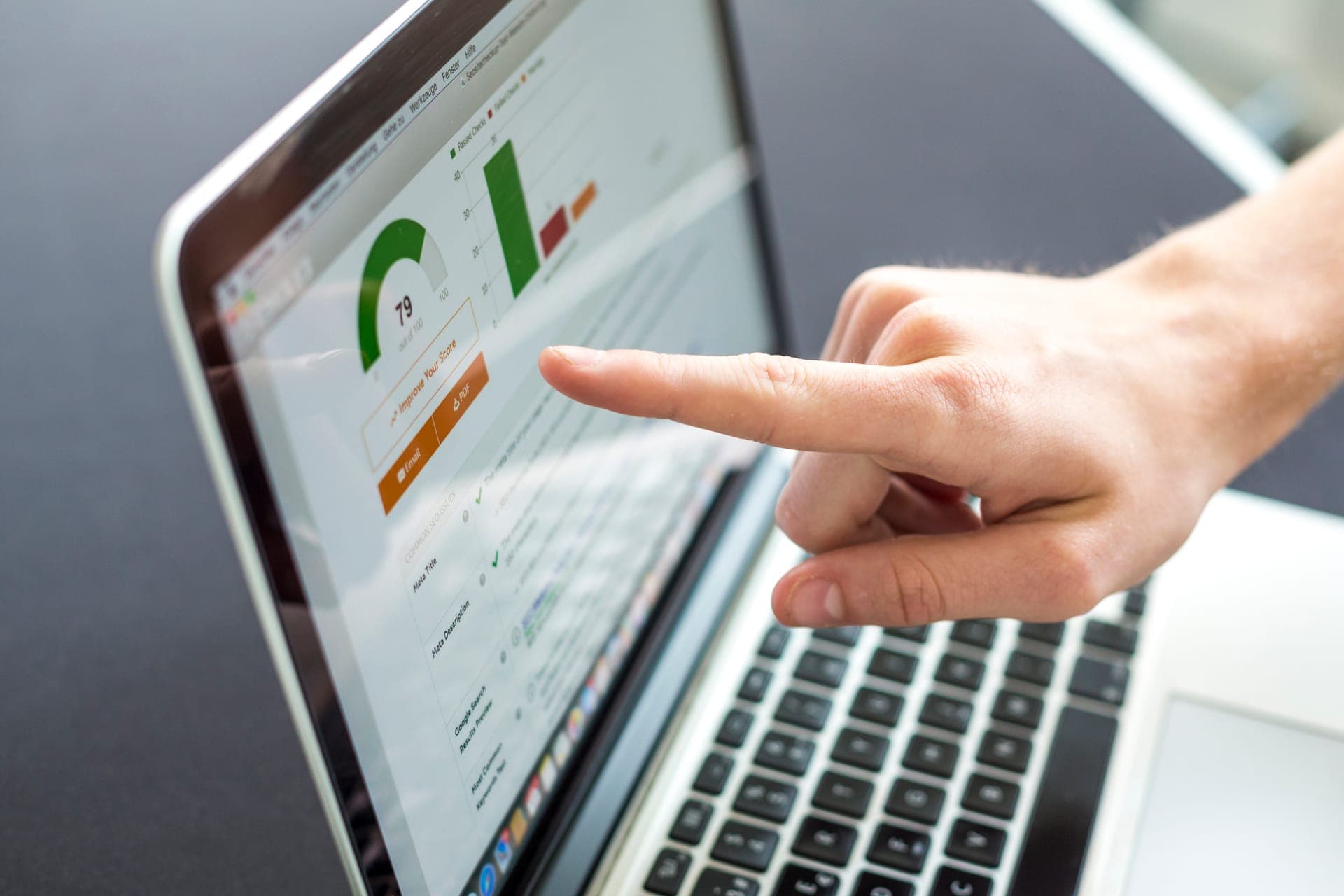 Hand wijst op laptop-scherm met website-data en analyse
